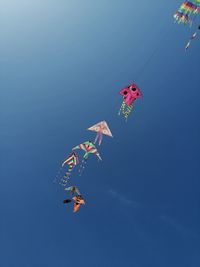 Low angle view of kites flying against blue sky