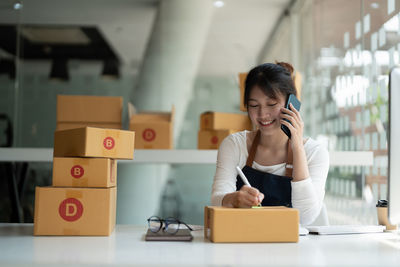 Young woman using mobile phone while sitting on table