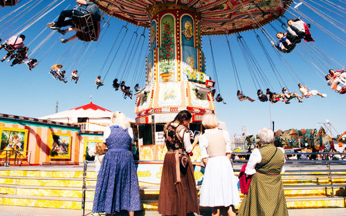 People at amusement park against sky