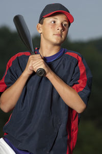 Portrait of a baseball player holding his bat wearing a warm up jacket