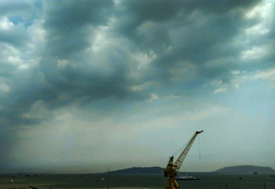 Silhouette of crane against cloudy sky