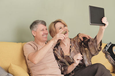 Friends using mobile phone while sitting on sofa at home