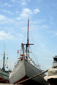 Sailboat moored at harbor against sky