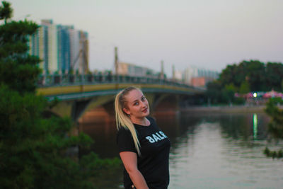 Portrait of smiling young woman standing against river