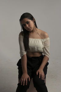 Portrait of young woman standing against gray background