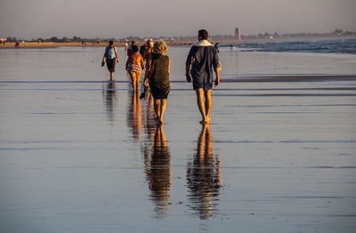 Rear view of people walking on beach