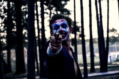 Portrait of smiling man with face paint aiming handgun