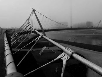Suspension bridge in city against sky