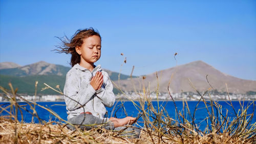 Girl doing yoga by lake