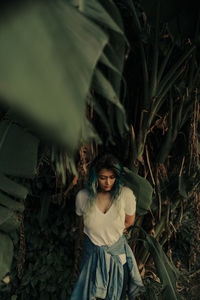 Thoughtful young woman standing by plants