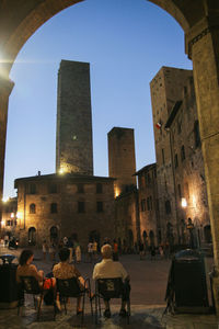 People in illuminated city against clear sky