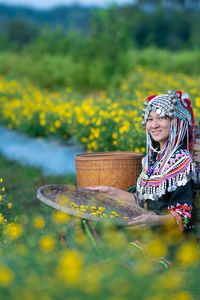 Woman wearing hat while standing by yellow flowers