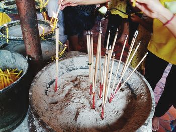 Midsection of people by incense sticks in temple