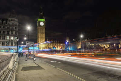 Light trails by big ben in city at night