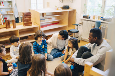 High angle view of teachers and students sitting in child care classroom