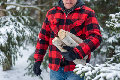 Man standing on snow covered tree