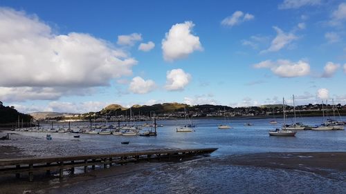 Boats moored at harbor against sky