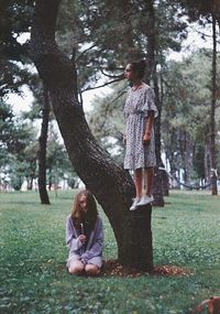 Young couple sitting on grass against trees