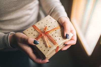 Midsection of woman holding gift box against illuminated lights