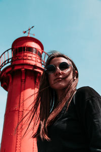 Low angle view of woman wearing sunglasses standing against clear sky