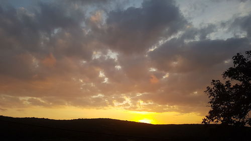 Silhouette landscape against dramatic sky during sunset