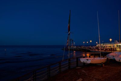 Sailboats moored in sea against clear blue sky