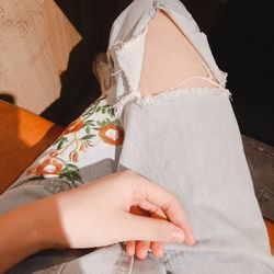 Low section of woman wearing torn jeans during sunny day