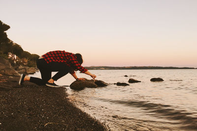 Full length side view of woman at beach against clear sky at dusk