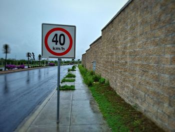 Road sign on footpath against sky