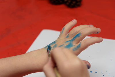 Cropped image of boy coloring hands on table