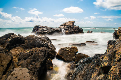 Scenic view of rocks in sea against sky