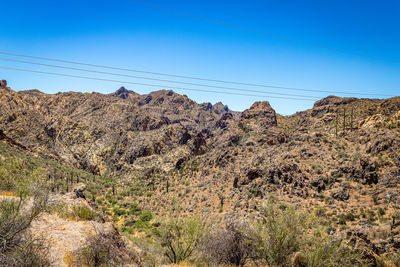 Low angle view of rocky mountains against clear blue sky