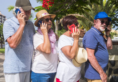 Senior people talking on phone standing outdoors