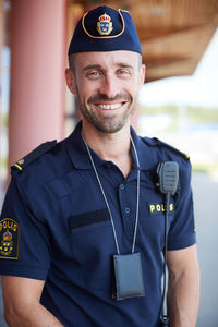 Portrait of smiling mid adult policeman standing outside police station