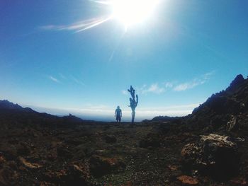 Man standing on mountain against blue sky