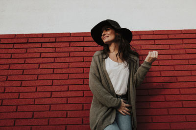 Young woman standing against brick wall