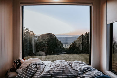 Rear view of woman sleeping on bed against landscape