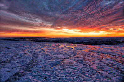 Scenic view of sea against dramatic sky during sunset