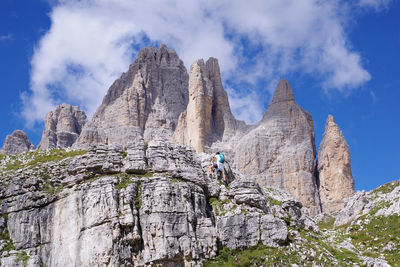 Low angle view of person on rocky mountain against sky