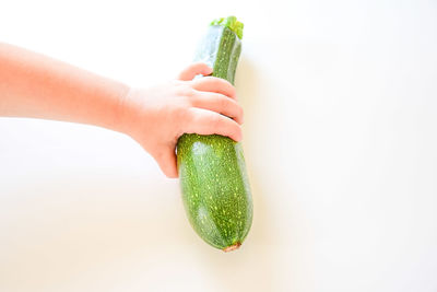 Close-up of hand holding fruit against white background