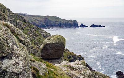 Rocks on shore by sea against sky