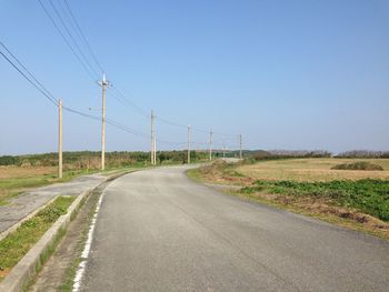 Road amidst field against clear sky