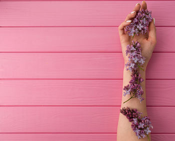 Cropped hands of woman holding flowers on table