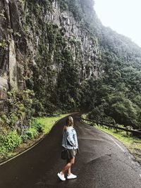 Rear view of woman walking on road amidst trees