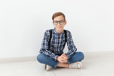 Portrait of teenage girl sitting against white background