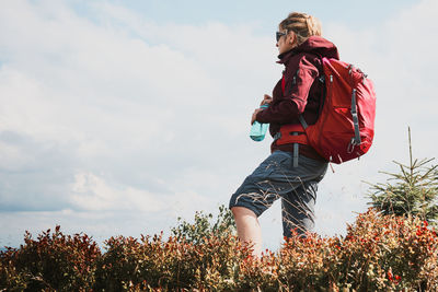 Woman with backpack hiking in mountains, spending summer vacation close to nature