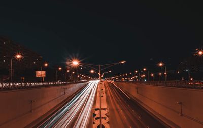 Light trails on road against sky at night