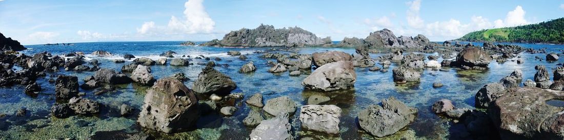 Panoramic view of rocks on beach against blue sky