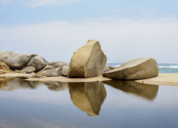 Reflection of rocks in lake against sky