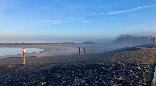 Road sign on misty coast landscape against blue sky